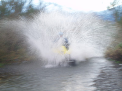 A child on a quad bike, utterly sending it into a body of water, creating a huge splash.