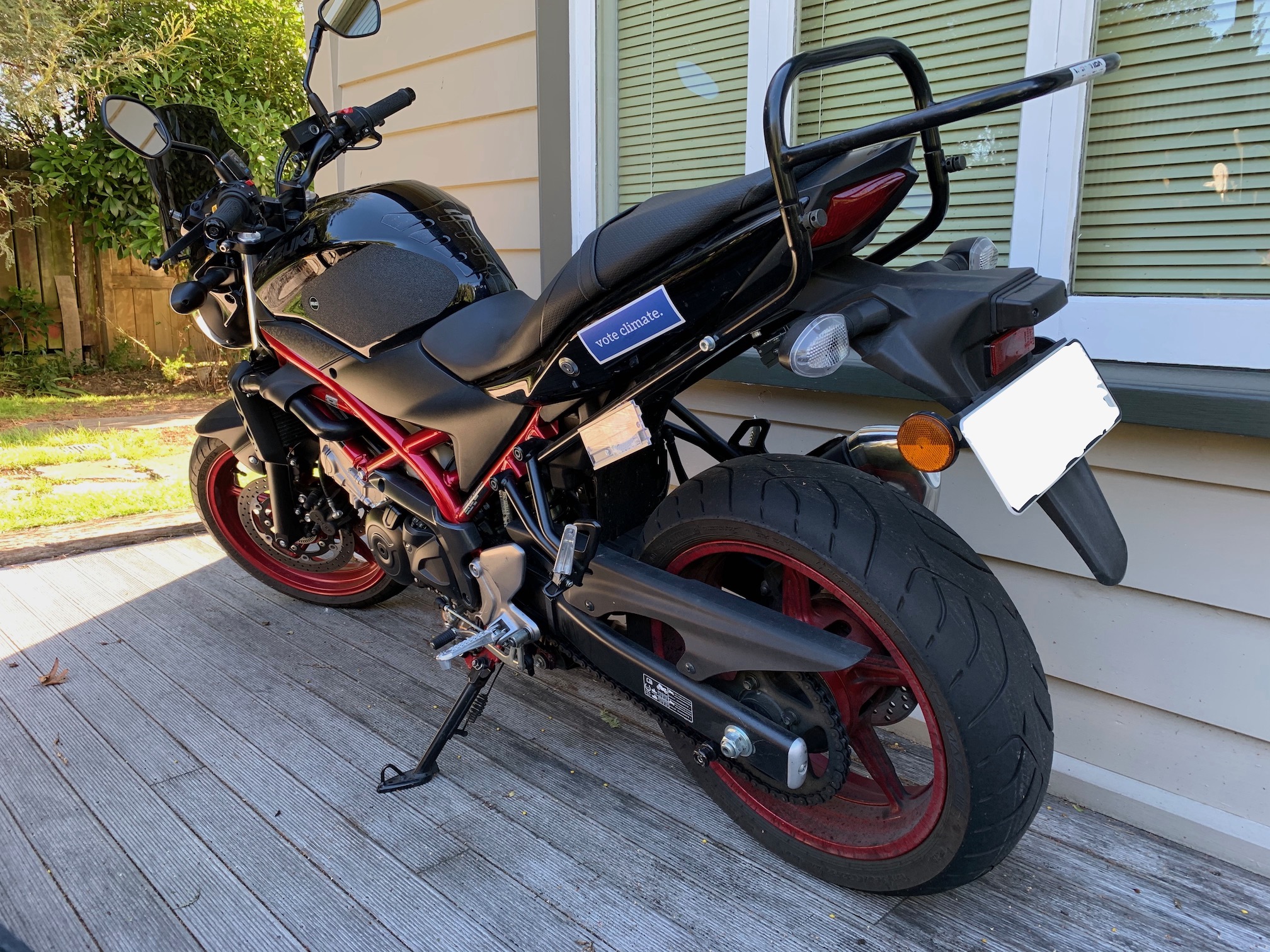 A blue sticker on a black motorbike saying "vote climate."