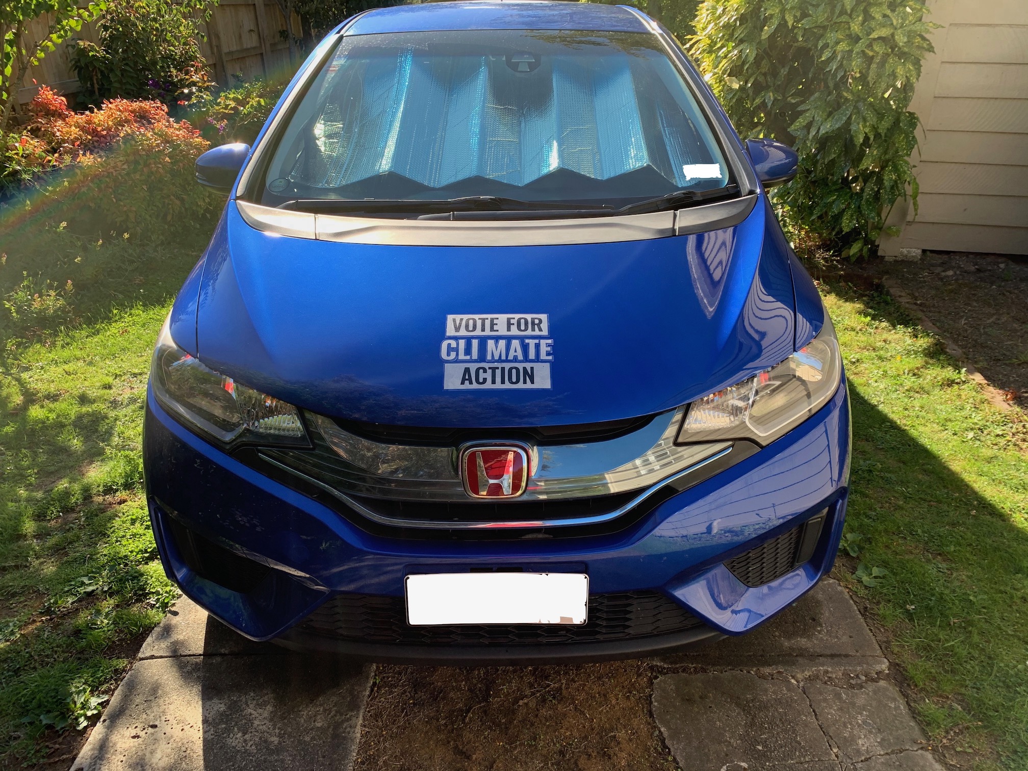 A big sticker on the front of a blue car saying "VOTE CLIMATE ACTION".